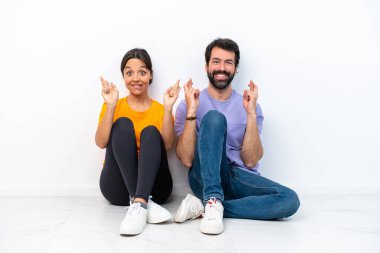 Beyaz arka planda izole bir şekilde yerde oturan genç beyaz bir çift.