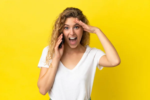 Sarı Arka Planda Cep Telefonu Kullanan Genç Sarışın Kadın Sürpriz — Stok fotoğraf