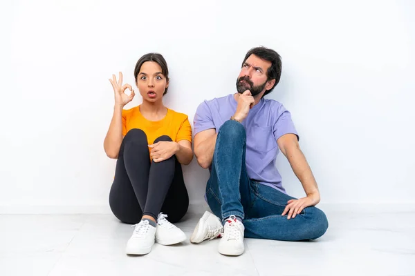Young Caucasian Couple Sitting Floor Isolated White Background Standing Thinking — 图库照片