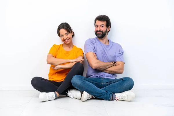 Young Caucasian Couple Sitting Floor Isolated White Background Keeping Arms — Foto de Stock