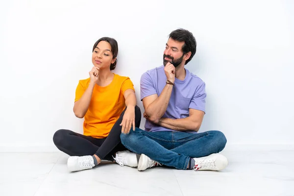 Young Caucasian Couple Sitting Floor Isolated White Background Looking Side — Foto de Stock