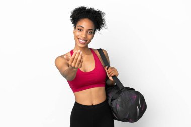 Spor çantalı genç Afro-Amerikan kadın mavi arka planda izole edilmiş, bizimle gelmesi için davet ediliyor. Gelmene sevindim.