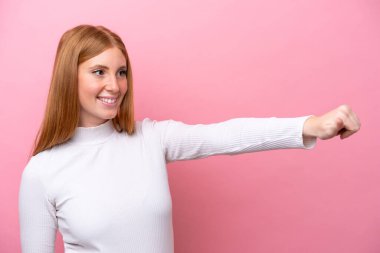 Pembe arka planda izole edilmiş genç, kızıl saçlı bir kadın baş parmak işareti yapıyor.