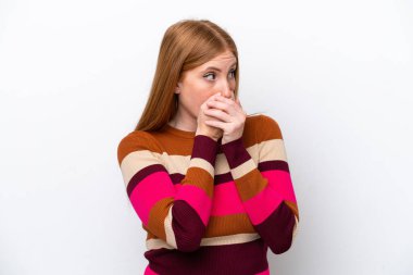 Genç kızıl saçlı kadın beyaz arka planda izole edilmiş ağzını kapatıyor ve yan tarafa bakıyor.