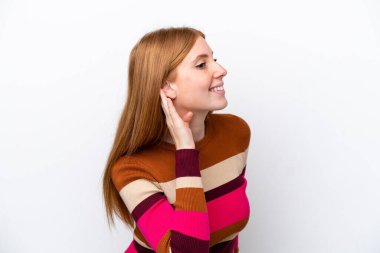 Genç kızıl saçlı kadın beyaz arka planda izole edilmiş. Kulağına elini sürerek bir şeyler dinliyor.