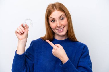 Beyaz arka planda izole edilmiş görünmez diş telleri tutan genç kızıl saçlı kadın.