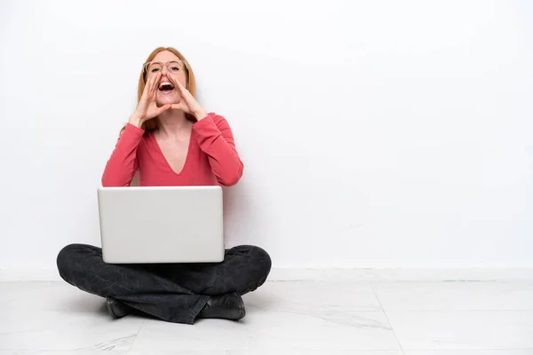 Молодая Рыжая Женщина Ноутбуком Сидящая Полу Изолированы Белом Фоне Кричать — стоковое фото