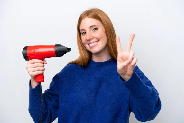 Jonge Roodharige Vrouw Met Een Haardroger Geïsoleerd Witte Achtergrond Glimlachen — Stockfoto