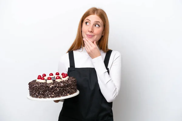 若いです赤毛女性保持誕生日ケーキ隔離上の白い背景上を見上げます上の笑顔 — ストック写真