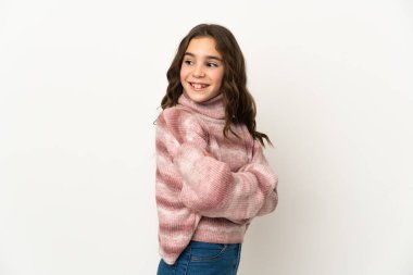 Beyaz arka planda izole edilmiş küçük beyaz kız yana bakıyor ve gülümsüyor.