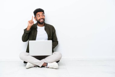 Dizüstü bilgisayarı olan genç Brezilyalı bir adam beyaz zeminde izole bir şekilde oturuyor. Çözümü bulmak için parmağını kaldırıyor.