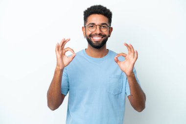 Beyaz arka planda izole edilmiş genç Brezilyalı iki eliyle tamam işareti gösteriyor.