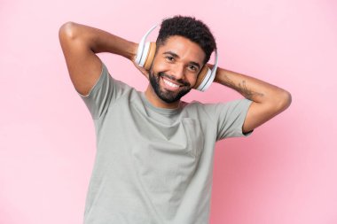 Pembe arka planda izole edilmiş genç Brezilyalı adam müzik dinliyor.
