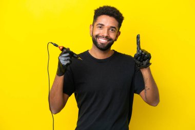 Dövmeli adam Brezilyalı izole edilmiş sarı arka planda harika bir fikre işaret ediyor.