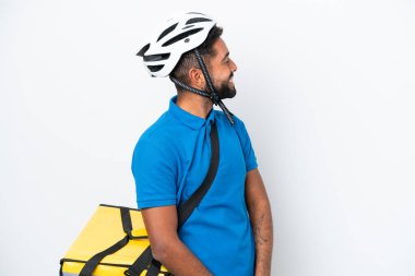 Termal sırt çantalı genç Brezilyalı adam beyaz arka planda izole edilmiş. Yan pozisyonda gülüyor.