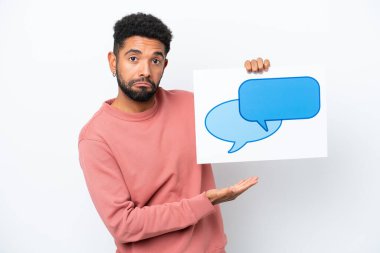 Genç Brezilyalı bir adam beyaz arka planda izole edilmiş. Elinde konuşma balonu ikonu olan bir levha var.