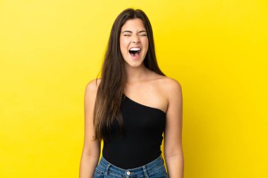 Genç Brezilyalı bir kadın sarı arka planda izole edilmiş ve ağzı açık bağırıyor.
