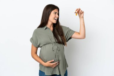 Genç Brezilyalı bir kadın beyaz arka planda izole edilmiş hamile ve emzik taşıyor.