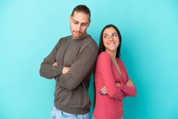 Young Caucasian Couple Isolated Blue Background Keeping Arms Crossed Looking — Stock Photo, Image