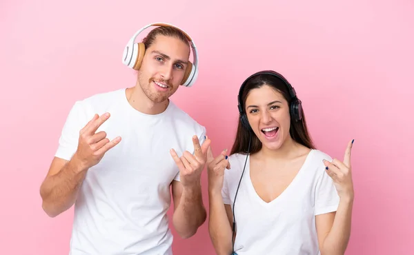 Joven Pareja Caucásica Aislada Sobre Fondo Rosa Escuchando Música Haciendo —  Fotos de Stock