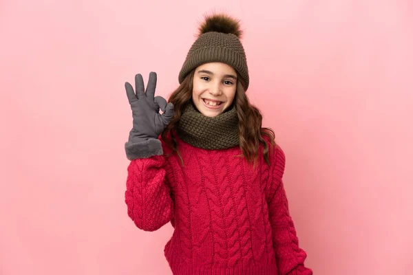 분홍색 배경에 고립된 모자를 소녀는 손가락으로 사인을 — 스톡 사진