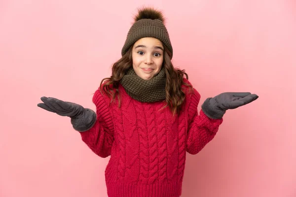 Malá Dívka Zimní Klobouk Izolované Růžovém Pozadí Pochybnostmi Při Zvedání — Stock fotografie