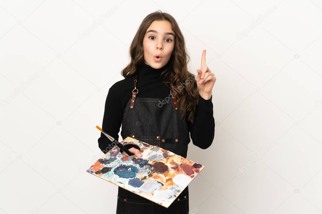 Little artist girl holding a palette isolated on white background intending to realizes the solution while lifting a finger up