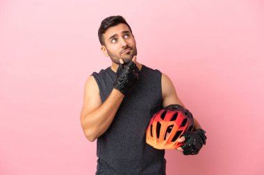 Pembe arka planda izole edilmiş genç bisikletçinin şüpheleri var.