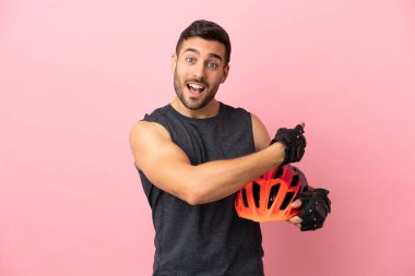 Pembe arka planda izole edilmiş genç bisikletçi.