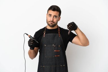 Dövme sanatçısı beyaz arkaplanda izole edilmiş, başparmağı negatif ifade ile aşağı gösteren