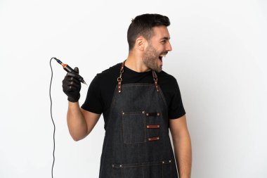 Dövme sanatçısı beyaz arka planda izole edilmiş. Yan pozisyonda gülüyor.