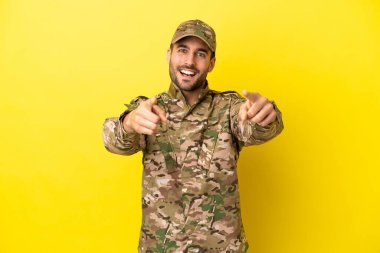 Sarı arka planda izole edilmiş bir asker sana gülümserken işaret ediyor.