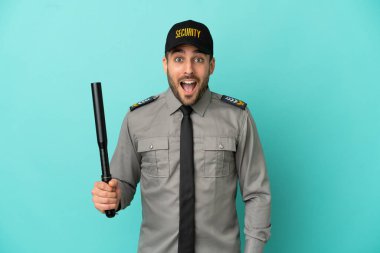 Genç güvenlik elemanı mavi arka planda şaşırmış yüz ifadesi ile izole edilmiş.