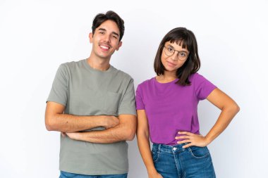 Genç çift, izole edilmiş beyaz arka planda kollarını kalçalarına dayayıp gülümseyerek poz veriyor.