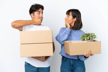 Genç bir çift, uygunsuz bir şey söyledikleri için ağızlarını kapayarak beyaz arka planda izole edilmiş eşyalarla dolu bir kutuyu alırken hamle yapıyor.