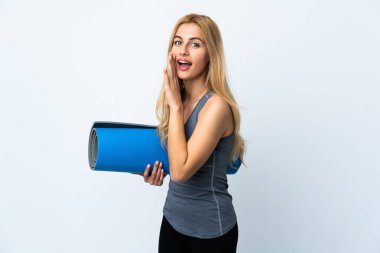 Genç sporcu kadın yoga derslerine giderken elinde paspas, beyaz arka planda bir şeyler fısıldıyor.