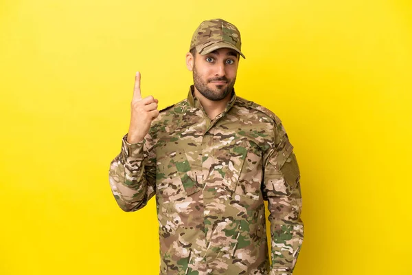 Στρατιωτικός Άνθρωπος Απομονωμένος Κίτρινο Φόντο Δείχνοντας Δείκτη Μια Μεγάλη Ιδέα — Φωτογραφία Αρχείου