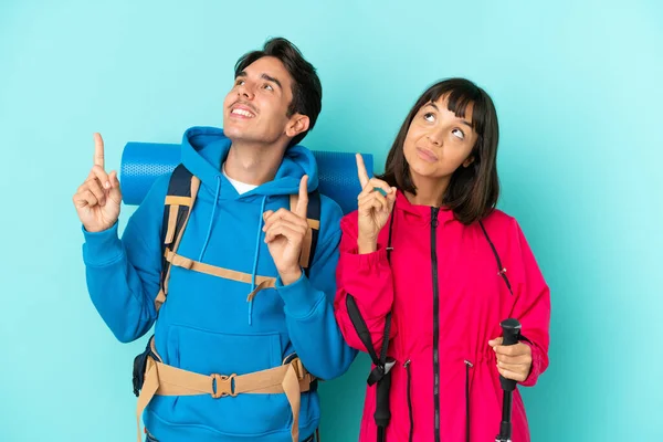 Pareja Jóvenes Montañeros Aislados Sobre Fondo Azul Señalando Con Dedo —  Fotos de Stock