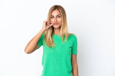 Sarışın Uruguaylı kız beyaz arka planda izole edilmiş ve sessizlik işareti gösteriyor.