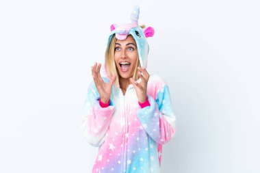 Sarışın Uruguaylı kız tek boynuzlu at pijaması giyiyor. Beyaz arka planda izole edilmiş ve yüzünde sürpriz bir ifade var.