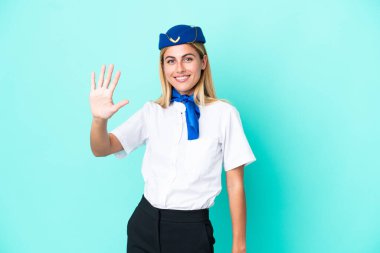 Uçak hostesi Uruguaylı kadın mavi arka planda izole edilmiş, parmaklarıyla beşi sayıyor.