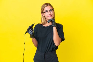 Dövme sanatçısı Uruguaylı kadın sarı arka planda izole edilmiş gülümserken yukarı bakıyor