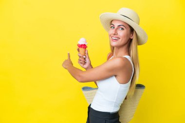 Sarışın Uruguaylı yaz kızı elinde dondurma tutarken sarı arka planda izole edilmiş.
