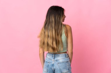 Genç beyaz kadın pembe arka planda izole edilmiş arka planda ve yan bakıyor.