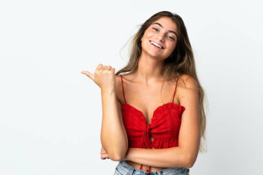 Beyaz arka planda izole edilmiş genç beyaz kadın bir ürünü sunmak için kenarı işaret ediyor.