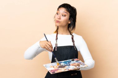 Soyutlanmış arka planda palet tutan genç sanatçı.