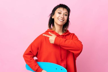 Genç Uruguaylı kadın pembe arka planda paten kayıyor ve yan tarafı gösteriyor.