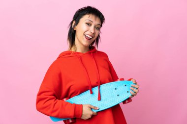 Genç Uruguaylı kadın pembe arka planda mutlu bir ifadeyle paten kayıyor.