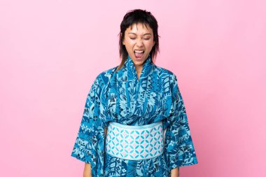 Kimono giyen genç bir kadın, izole edilmiş mavi arka planda, ağzı açık bir şekilde öne doğru bağırıyor.