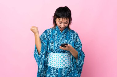 Kimono giyen genç bir kadın mavi arka planda şaşırdı ve bir mesaj gönderiyor.